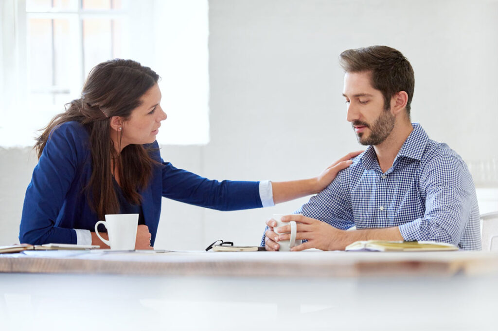 women consoling a man at work
